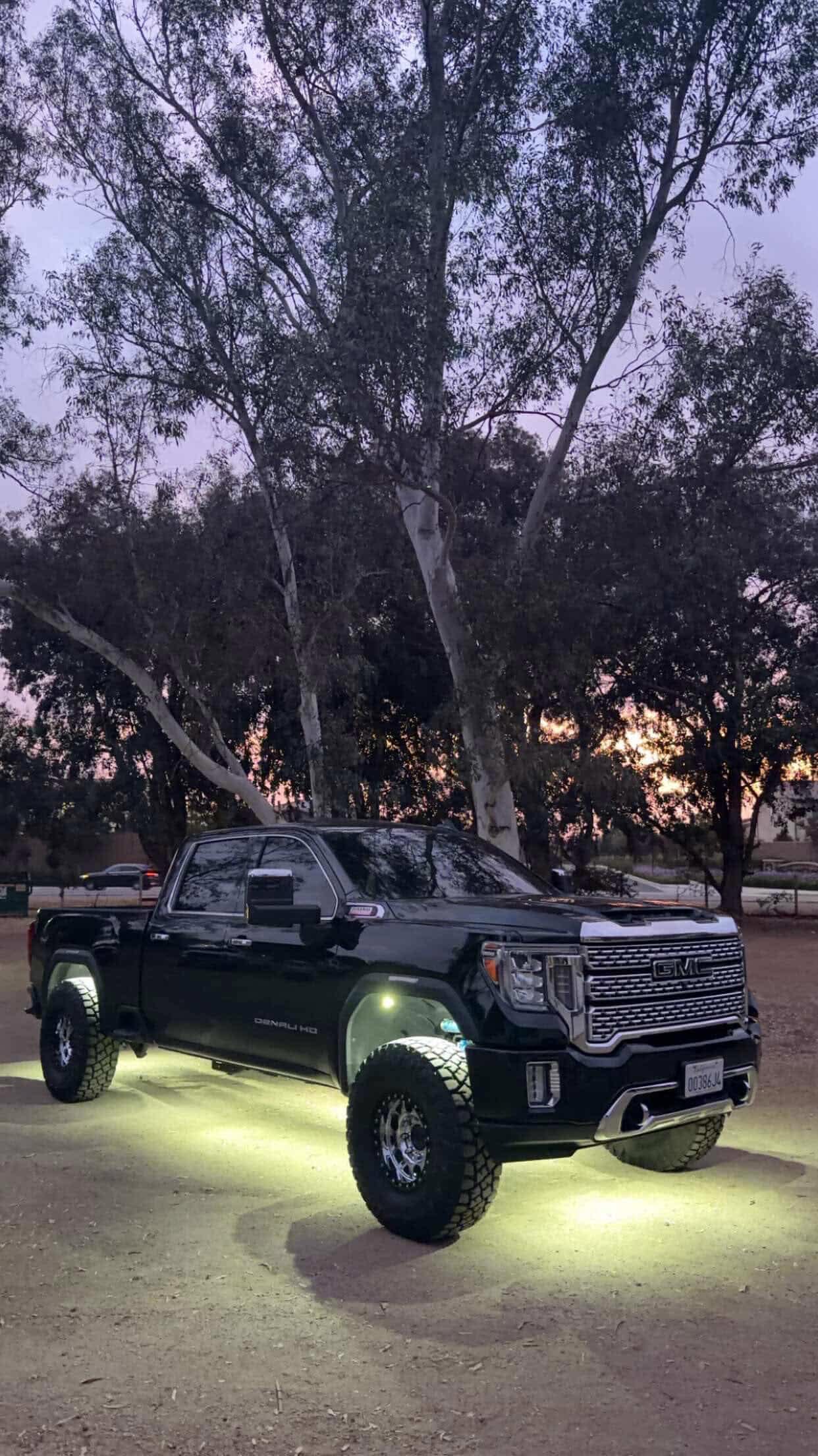 GMC Denali HD with white underbody glow on gravel